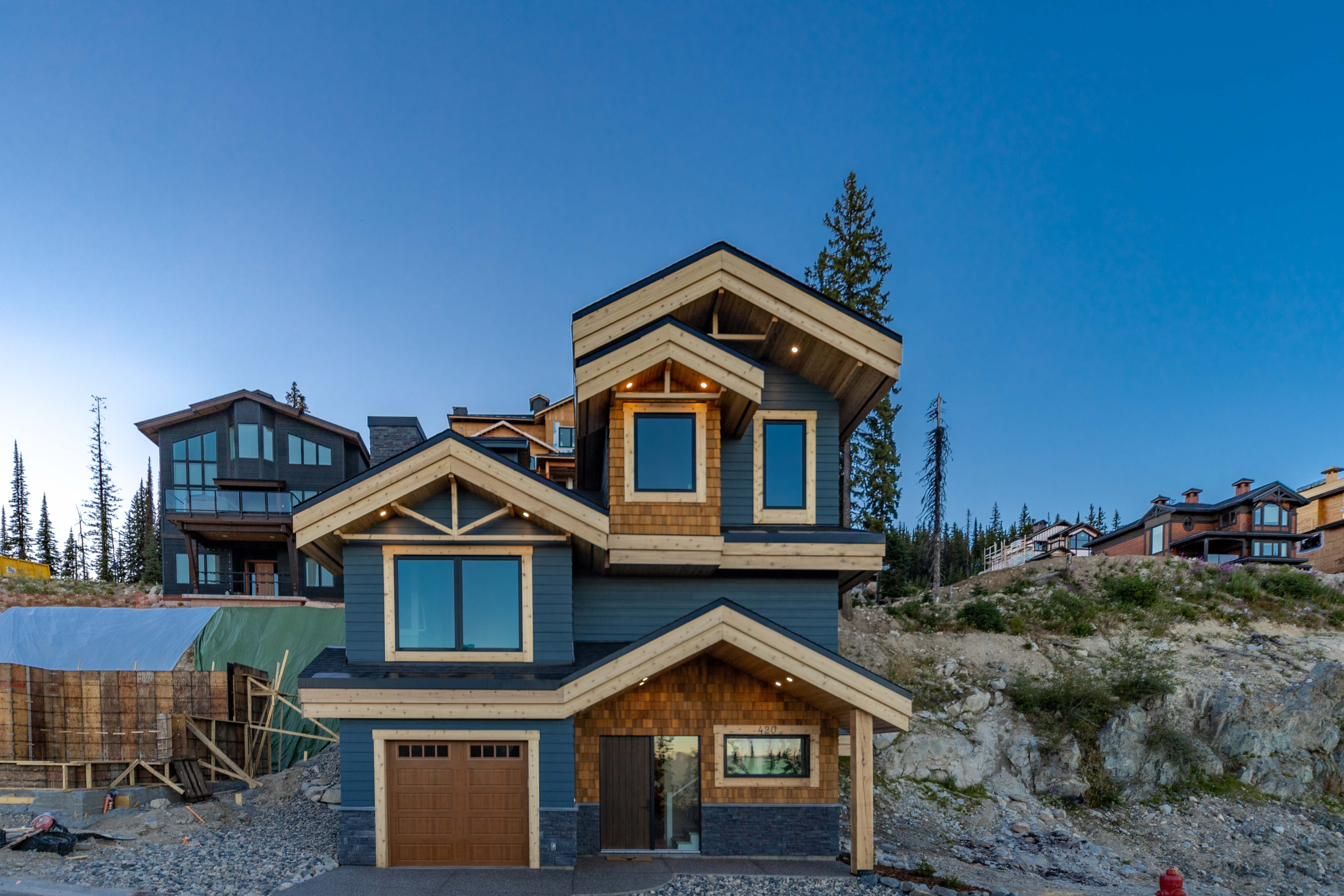 420 Feathertop exterior. Blue custom home with wood accents at Big White, built by North Grove Homes